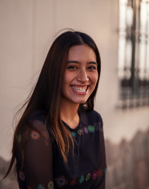 Portrait of a smiling woman against a colonial wall in Cusco