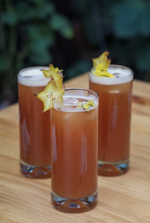 Three chilcano cocktails garnished with starfruit on a wooden table