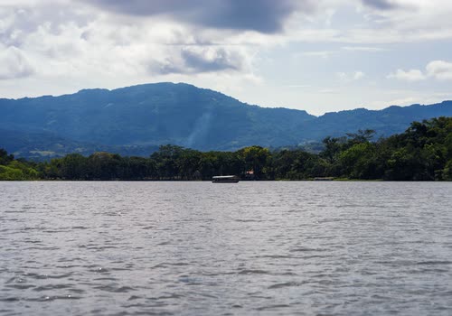 A wide river below forested mountains under a broken sky in northern Peru