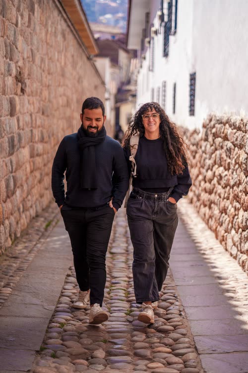 A couple walking a cobbled lane between Inca stone walls in Cusco