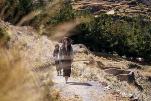 Two walkers on the stone path through the upper terraces of Machu Picchu