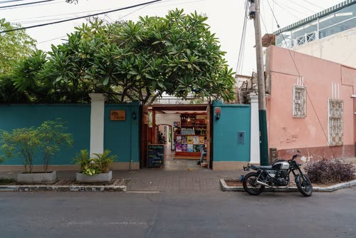 A small teal-fronted corner shop with a motorcycle parked outside