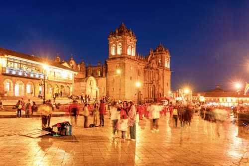 Cusco Cathedral floodlit above the crowds in the Plaza de Armas at dusk