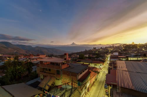 Sunset over the rooftops of an Andean town with mountains beyond