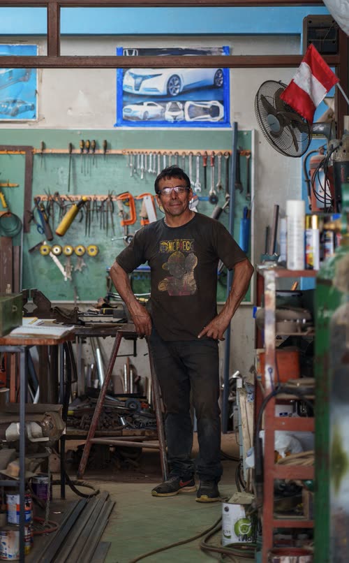 A metalworker standing in the doorway of his workshop in Peru