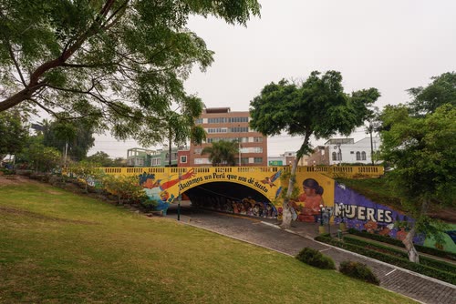 A mural-painted underpass in a green Lima park