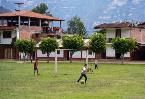 Children playing football on a village pitch below the Andes