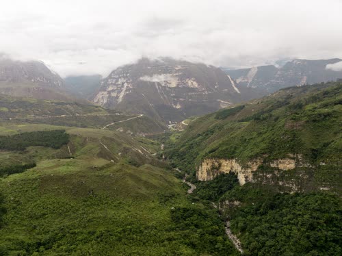 A green Andean valley under low cloud with limestone cliffs on the ridge line