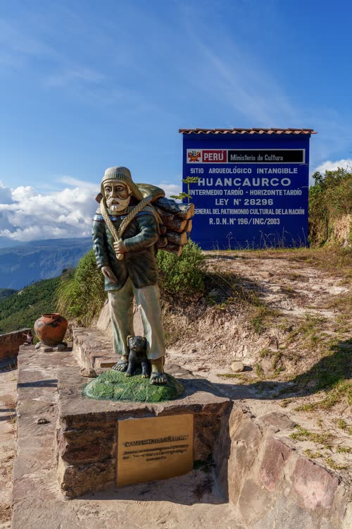 A statue and heritage sign at the Huancaurco archaeological site, Peru