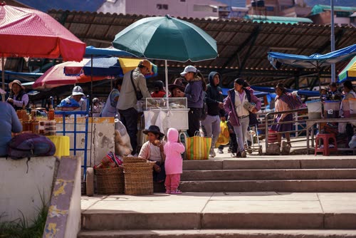 Shoppers and market umbrellas on the steps of an Andean town market
