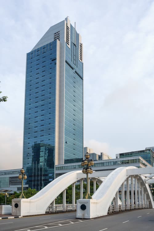 The white arches of a Singapore River bridge below an office tower