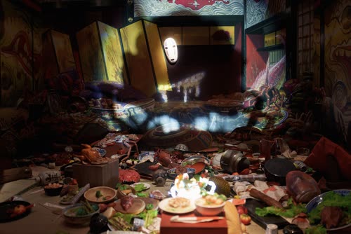 A No-Face figure among a banquet of food in a Studio Ghibli exhibition set