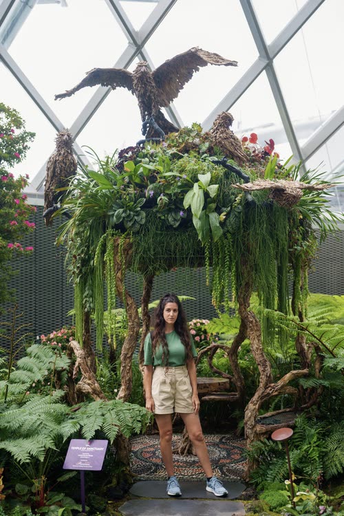 A woman beneath a hanging garden and driftwood bird sculpture, Singapore