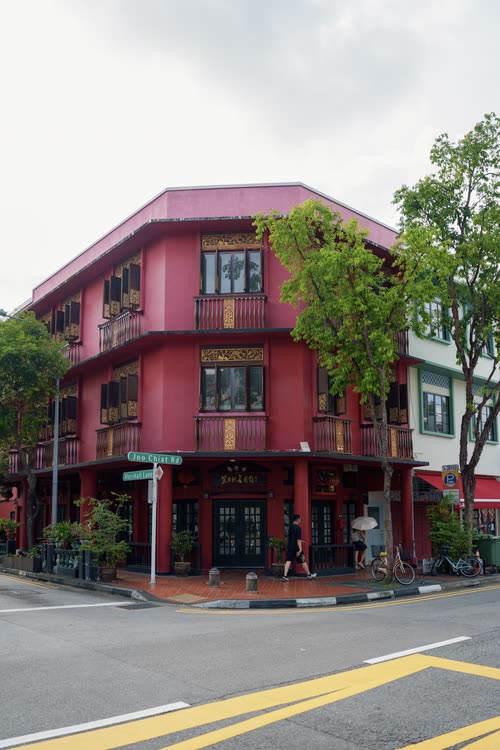 A deep pink corner shophouse with timber shutters, Singapore