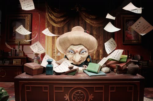 A model of Yubaba at her desk amid flying paper in a Studio Ghibli exhibition