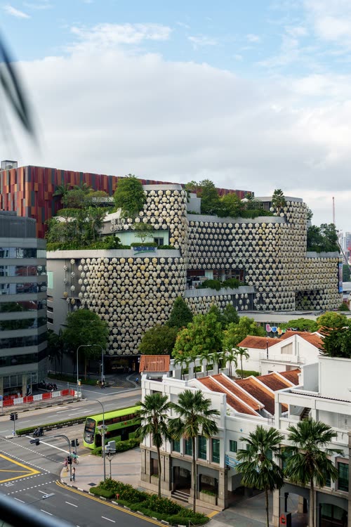 The perforated facade of a Singapore building above the street and shophouse roofs