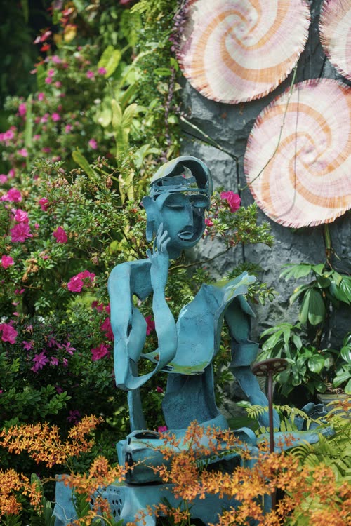 A blue figurative sculpture among orchids and shell forms, Singapore