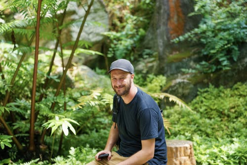 Jordy Scott sitting among tree ferns in the Singapore Botanic Gardens