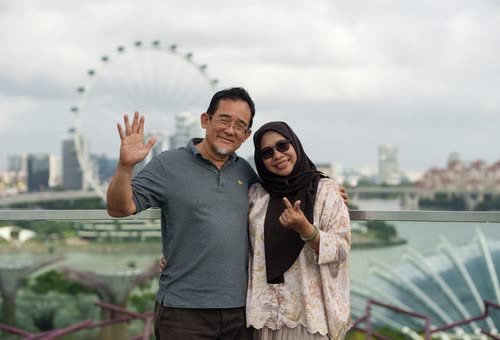 A couple posing with the Singapore Flyer and the bay behind them
