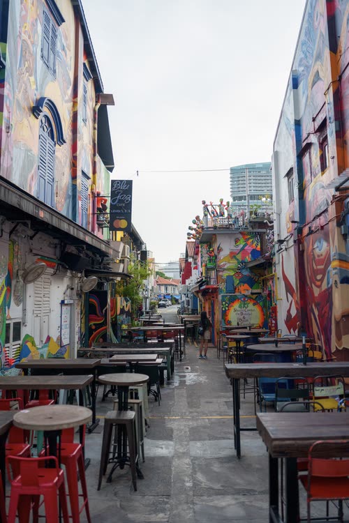 Empty tables in a mural-covered lane in the Kampong Glam district, Singapore