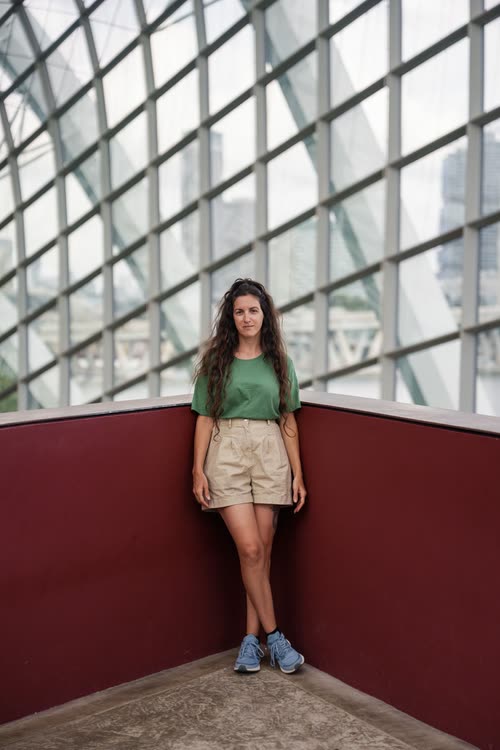 A woman standing against a red wall inside the Flower Dome, Singapore
