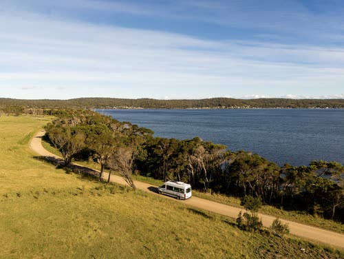 A campervan on a coastal track above a sheltered Tasmanian bay