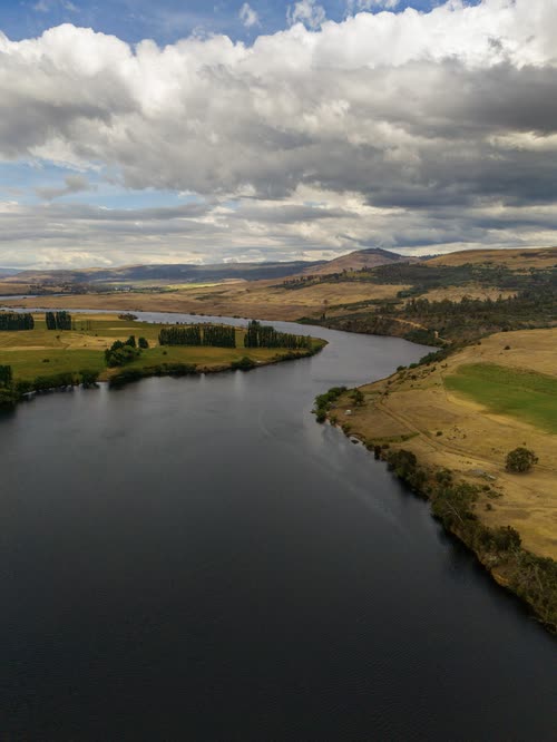 Aerial view of a broad river curving between farmland and bush, Tasmania