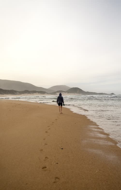 A lone walker on a wide empty beach in Tasmania