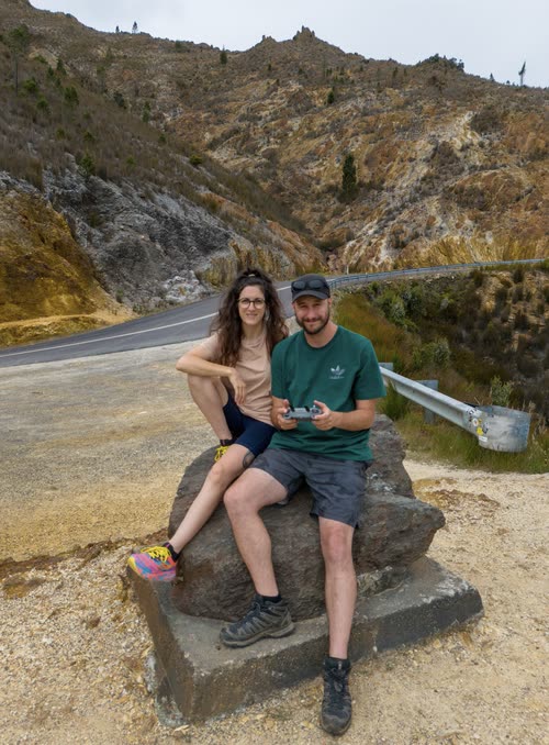 A couple sitting on a boulder beside a mountain road in Tasmania