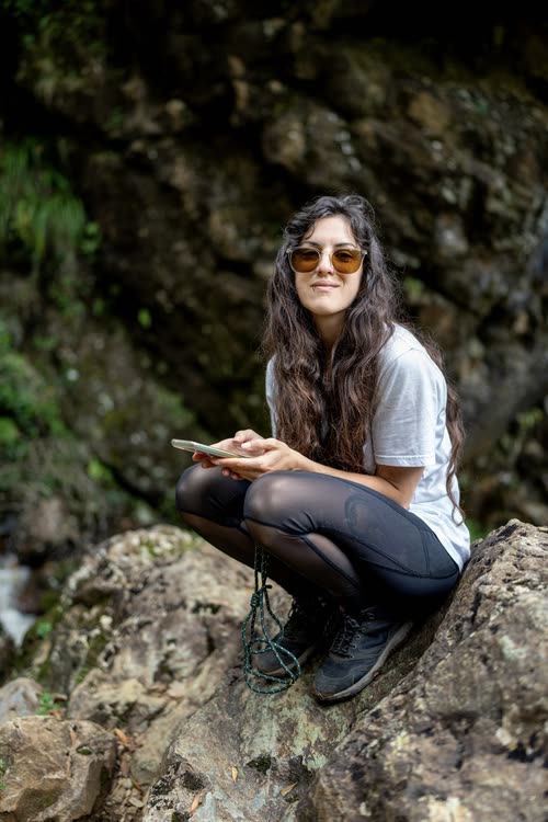 A woman crouching on rocks beside a Tasmanian waterfall