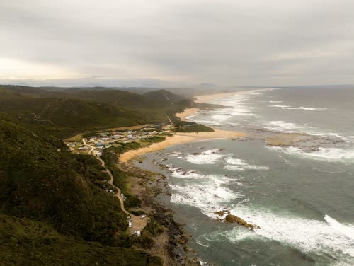Aerial view of a small coastal settlement above a long surf beach, Tasmania