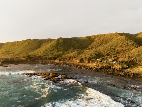 Aerial view of green headlands and reef on the Tasmanian coast