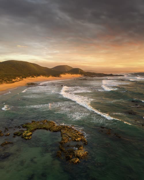 Aerial view of surf and reef at sunrise on a remote Tasmanian beach
