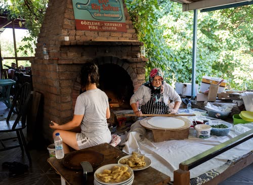 A woman making gozleme at a wood-fired oven in a Turkish village