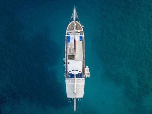 Aerial view straight down on a gulet anchored in deep blue water, Turkey