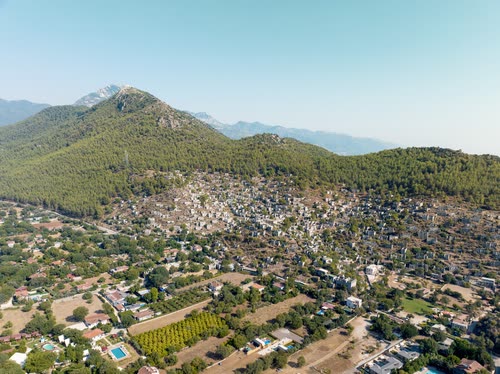 Aerial view of a coastal village among orchards below wooded peaks, Turkey