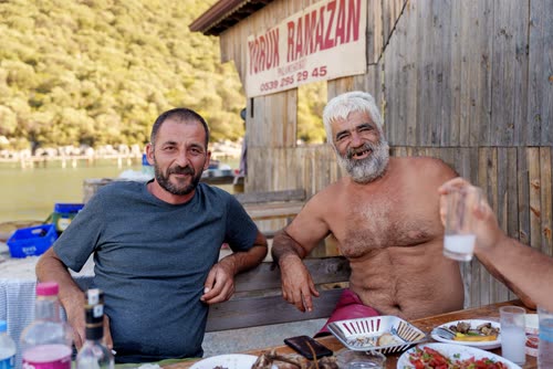 Two men at a table outside a timber waterside restaurant, Turkey