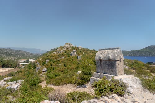 A Lycian sarcophagus standing on a scrubby hilltop above the coast, Turkey