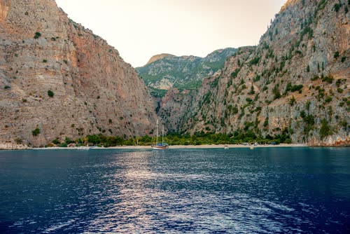 Steep pine and rock walls closing around the deep blue water of Butterfly Valley, Turkey