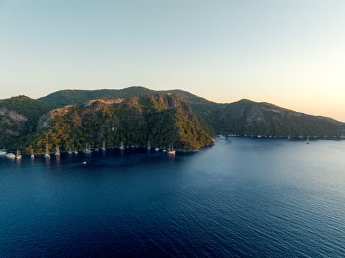 Aerial view of a wooded headland and anchored yachts at dusk, Turkey