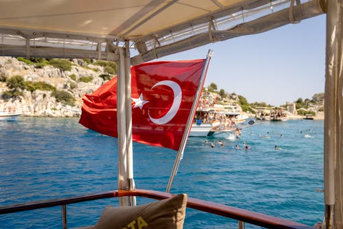 The Turkish flag flying from the stern of a gulet in a busy bay
