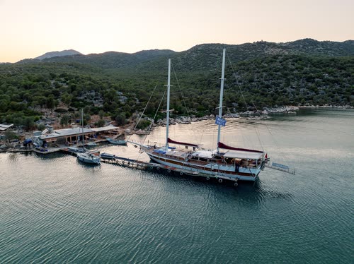Aerial view of a gulet moored at a jetty in a quiet bay at dusk, Turkey