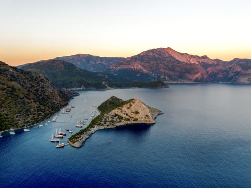 Aerial view of yachts moored around a headland at sunset, Turkey