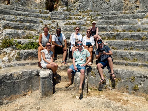 A tour group sitting on the stone tiers of an ancient theatre, Turkey
