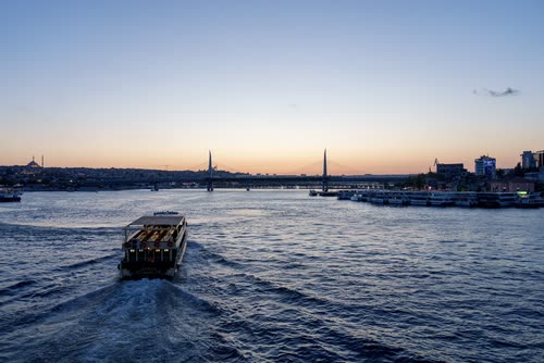 A ferry crossing the Bosphorus at dusk with the Istanbul skyline beyond
