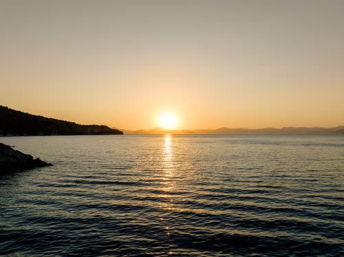 The sun setting over the sea beyond a dark headland, Turkey
