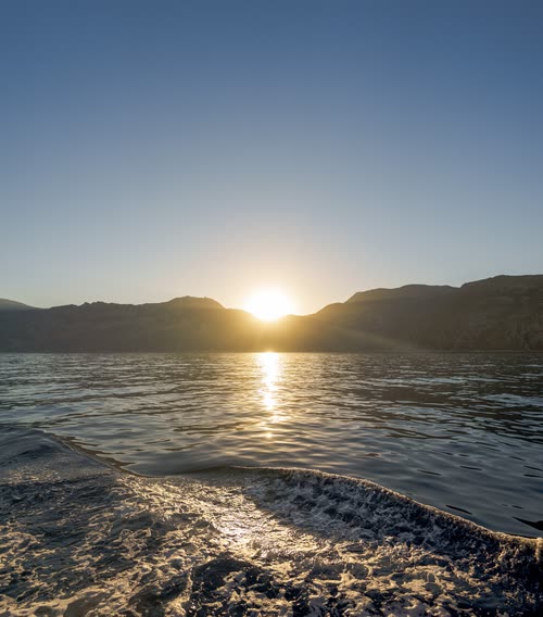The wake of a boat catching the low sun between two headlands, Turkey