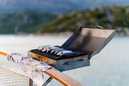 Fish grilling on a barbecue mounted on a boat rail, Turkey