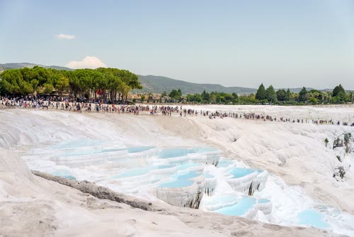 Visitors on the white travertine terraces and blue pools of Pamukkale, Turkey