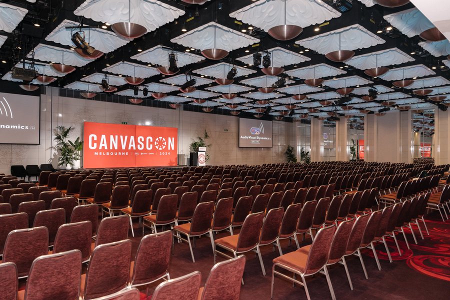 Conference room set with rows of seating facing a branded stage screen